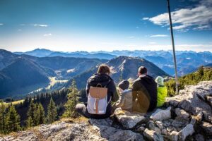 zdjęcia przedstawia dwoje siedzących turystów z plecakami, na szczycie góry